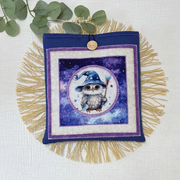 Funda de tela acolchada para saco de agua tamaño mediano, confeccionada a mano en algodón azul con cierre de botón de madera grabado y detalle decorativo de flecos de yute en la base.