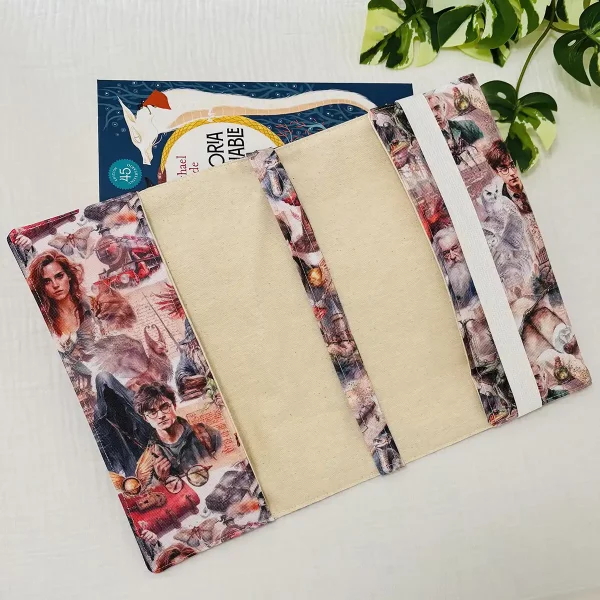 Interior de funda de libro artesanal abierta, con solapas laterales y elástico blanco para asegurar el libro, sobre fondo claro.