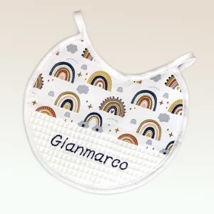 Babero personalizado de algodón con estampado de arcoíris y nombre bordado en hilo azul, ideal para bebés.