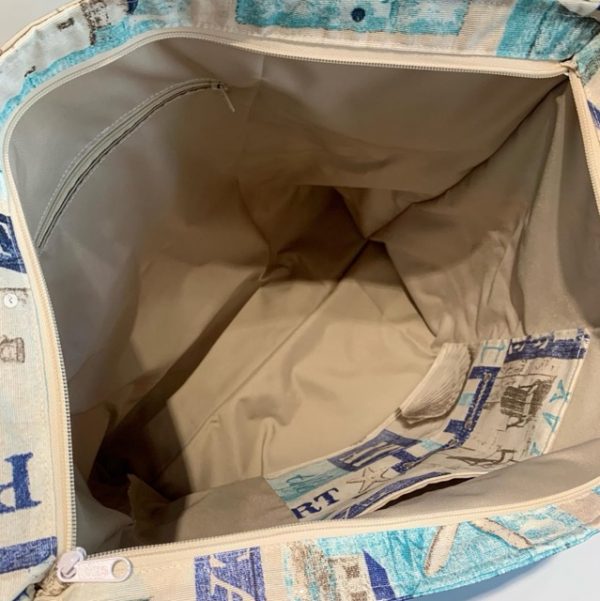 Vista del interior de la bolsa de playa grande, con forro beige, amplio espacio y bolsillo con cremallera para mayor organización